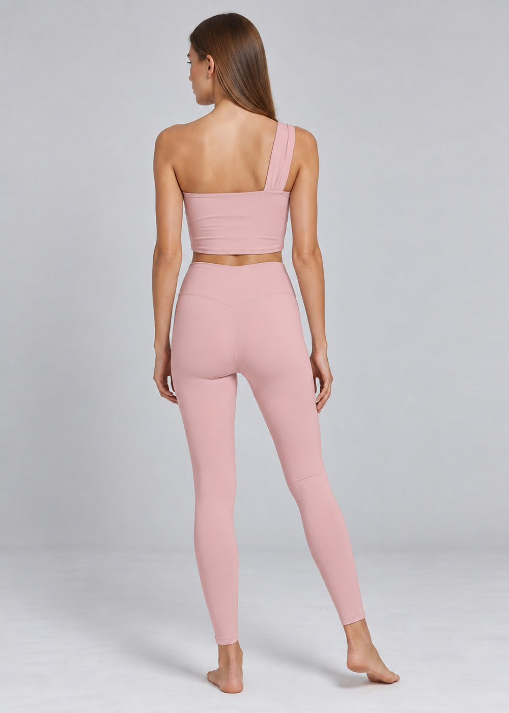 Back view of a blush pink one-shoulder crop top and high-waisted leggings activewear set