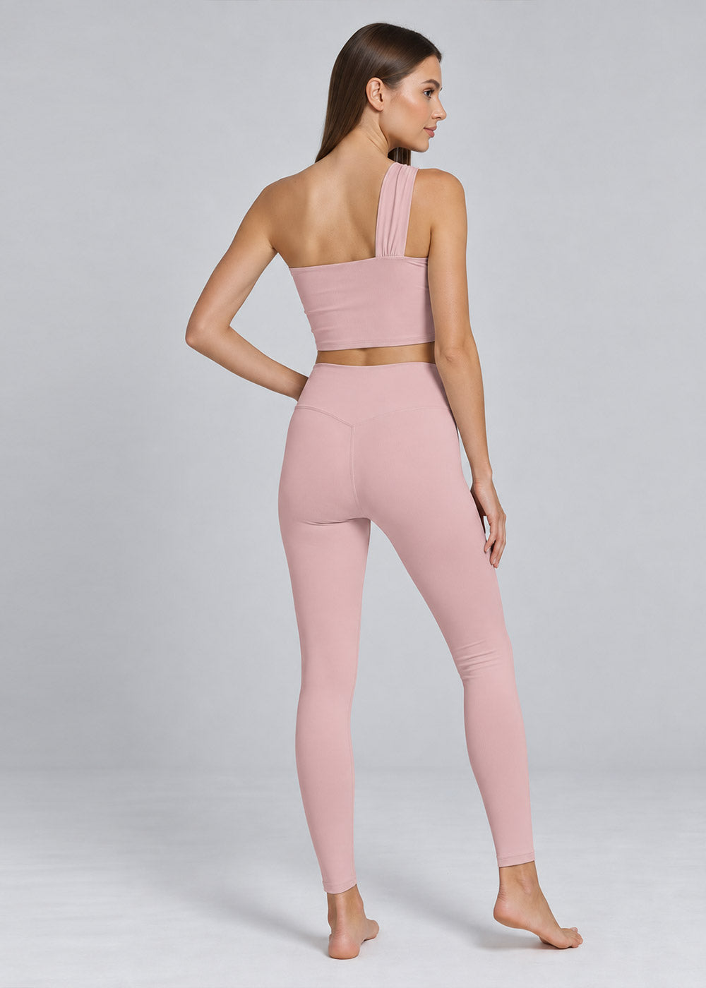 Back view of a blush pink one-shoulder crop top and high-waisted leggings activewear set