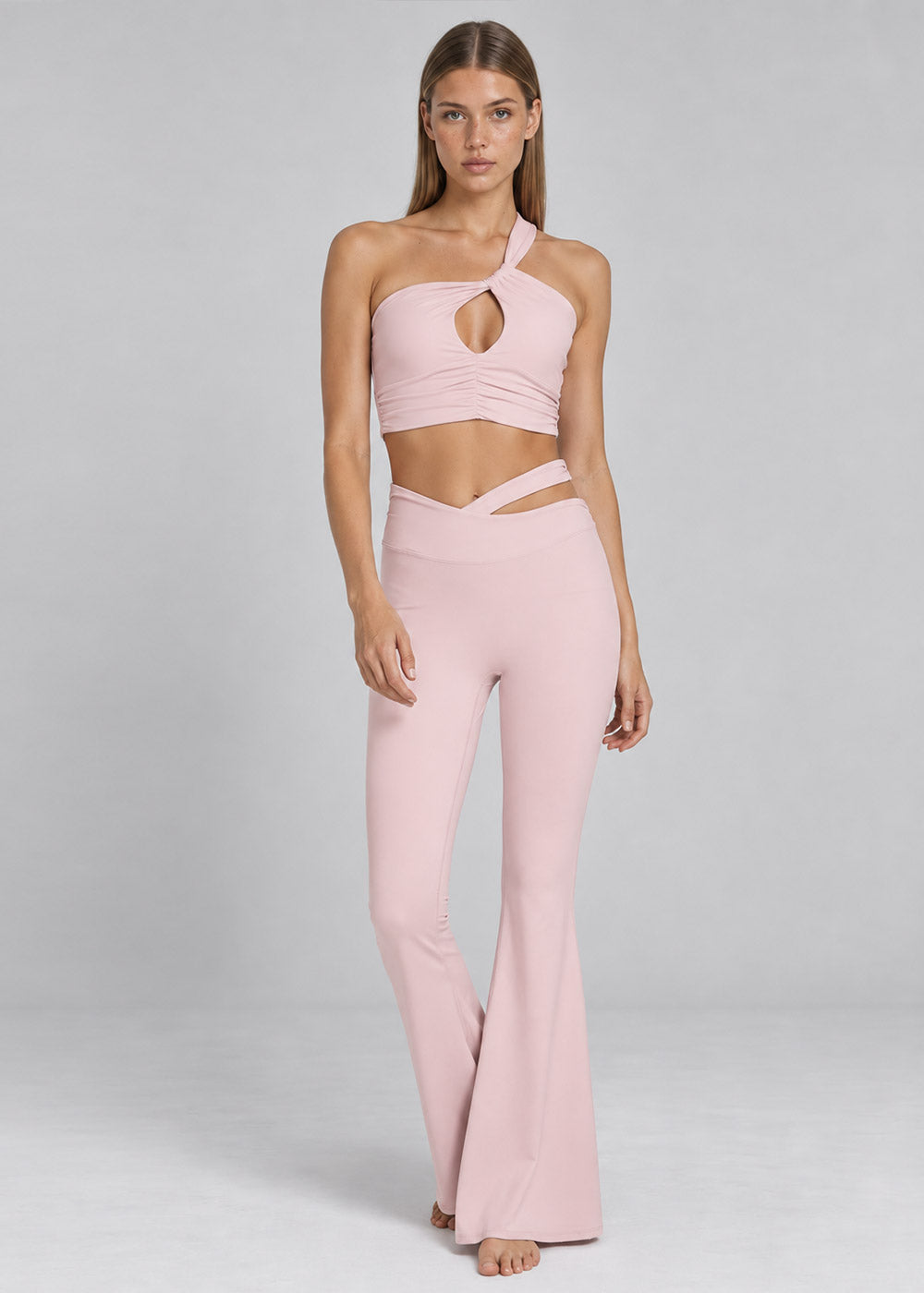 Front view of a blush pink one-shoulder cutout crop top with matching crossover-waist flare leggings