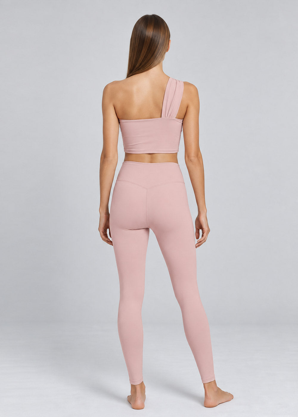 Back view of a blush pink one-shoulder crop top and high-waisted leggings activewear set