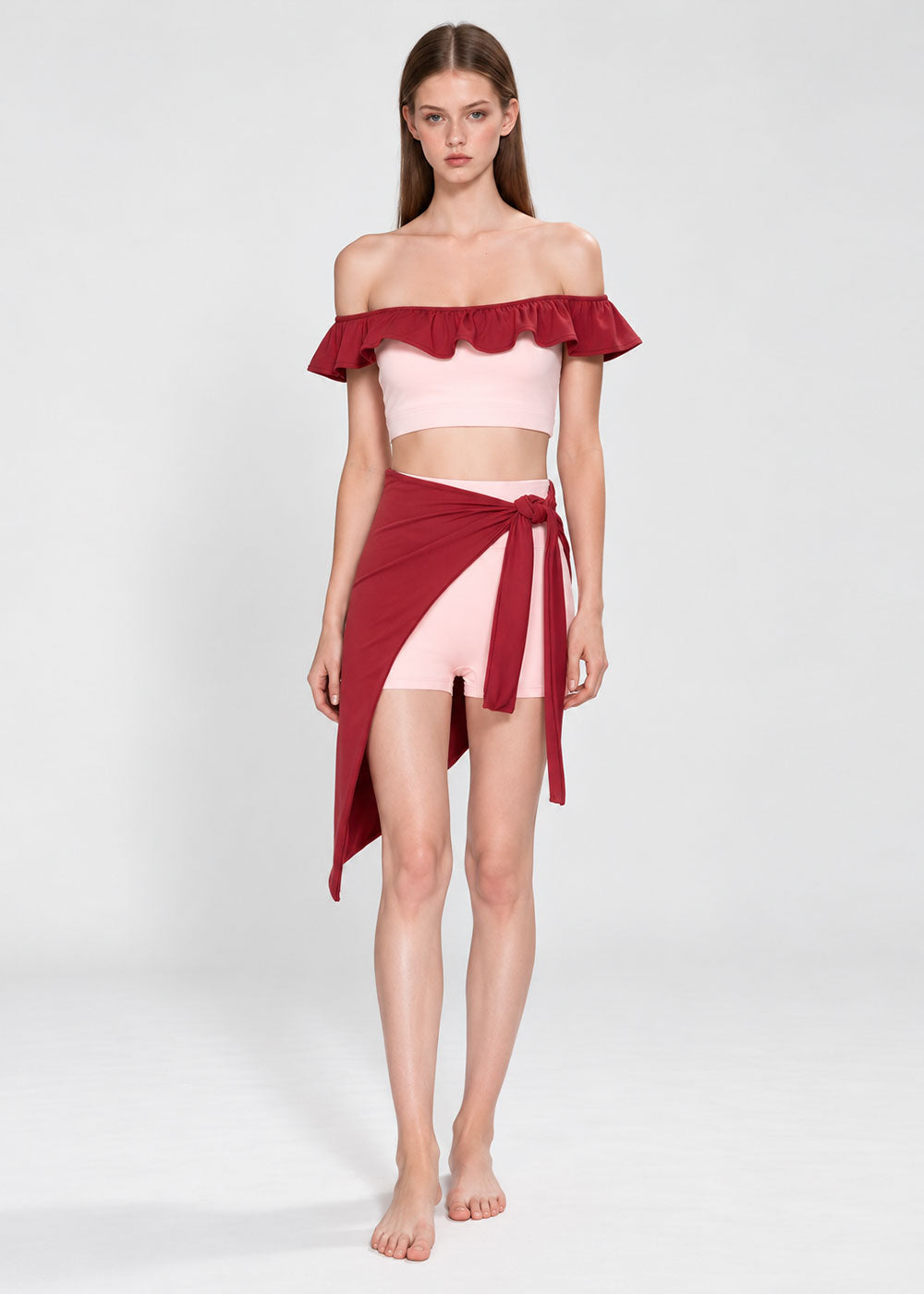 Women's blush pink off-shoulder ruffle crop top with burgundy trim, matching shorts and burgundy wrap skirt