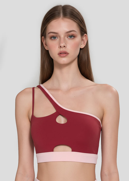 Burgundy asymmetrical sports bra for women with double straps, front cutouts and blush pink contrast trim