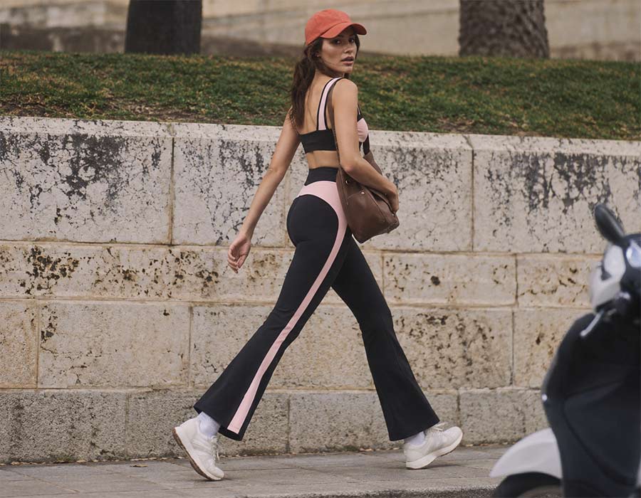 Woman wearing black and pink activewear with a sports bra and flare leggings from Flowglowear.
