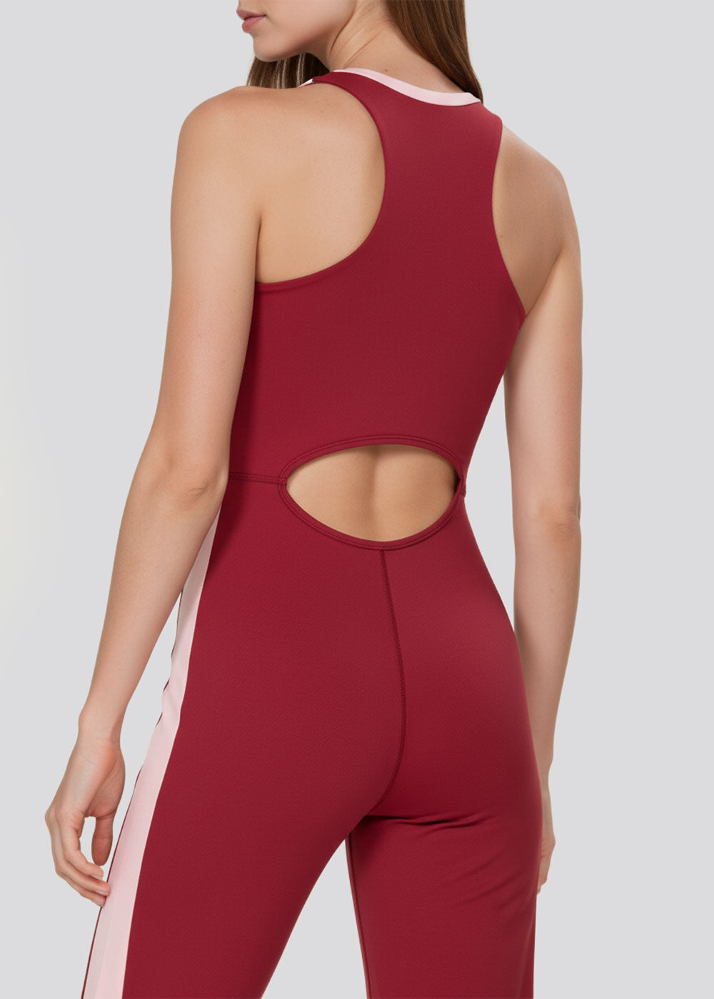 Back detail of a burgundy and blush pink colorblock jumpsuit featuring an oval waist cutout and racerback design